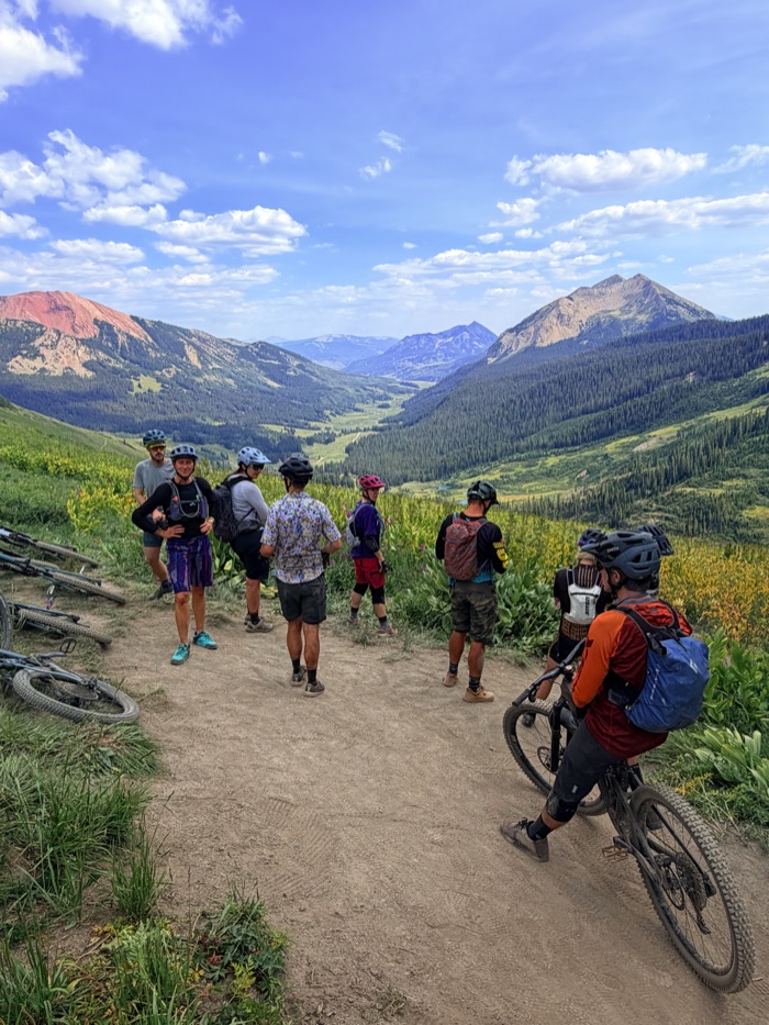 The group regrouping trailside above the valley with red peaks in the distance