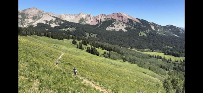 A lone rider on a meadow trail beneath the peaks above Crested Butte