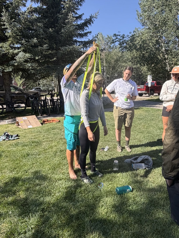 Practicing an improvised webbing rescue harness during a skills session