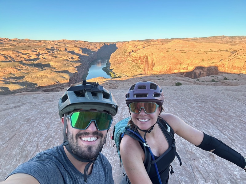 Two riders at a canyon rim overlook on a Moab ride